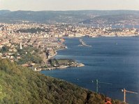 The photo is taken from above. Trees can be seen in the front, in the centre is water, surrounded by areas with different buildings on them.