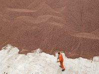 The photo is taken from above. A man can be seen in front of a mountain of cocoa.