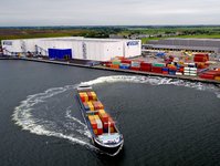 A ship loaded with containers is leaving a port. A Vollers building can be seen in the background