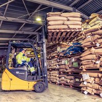 An employee stacks coffee bags on pallets using a forklift in the Moscow warehouse
