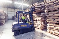 A woman sitting in a forklift in the coffee warehouse. She's choosing a coffee bag.
