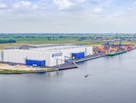 Three warehouses with the Vollers logo on them. On the right is the sea.