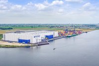 Three warehouses with the Vollers logo on them. On the right is the sea.