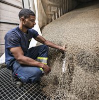 A young man is sitting in front of an open container, full with coffee beans.