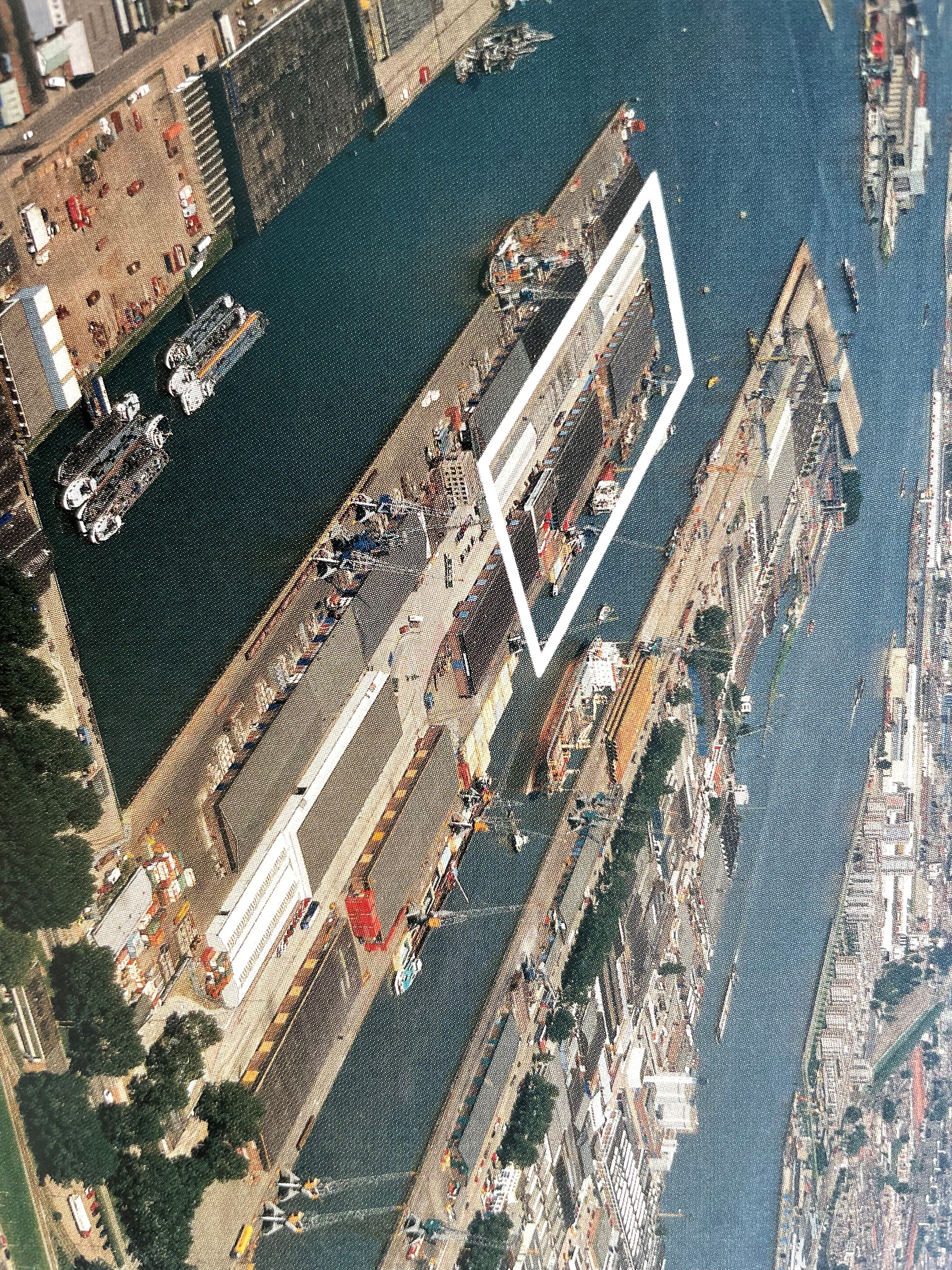 The photo is taken from above. There are four land parts with buildings and cars on them. The parts are seperated by water.